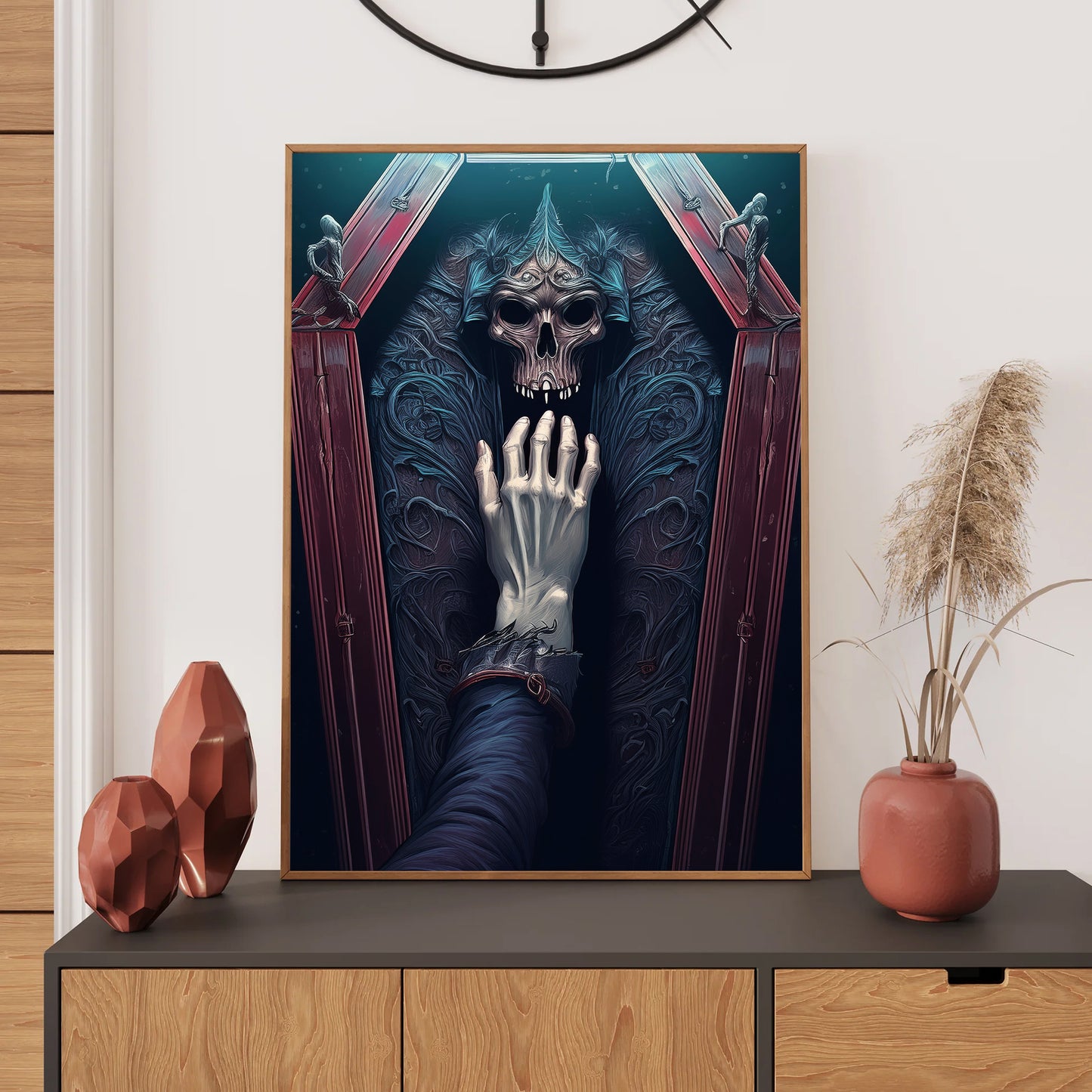 Framed artwork of a skeleton hand holding a skull on a wall above a wooden cabinet with decorative items.