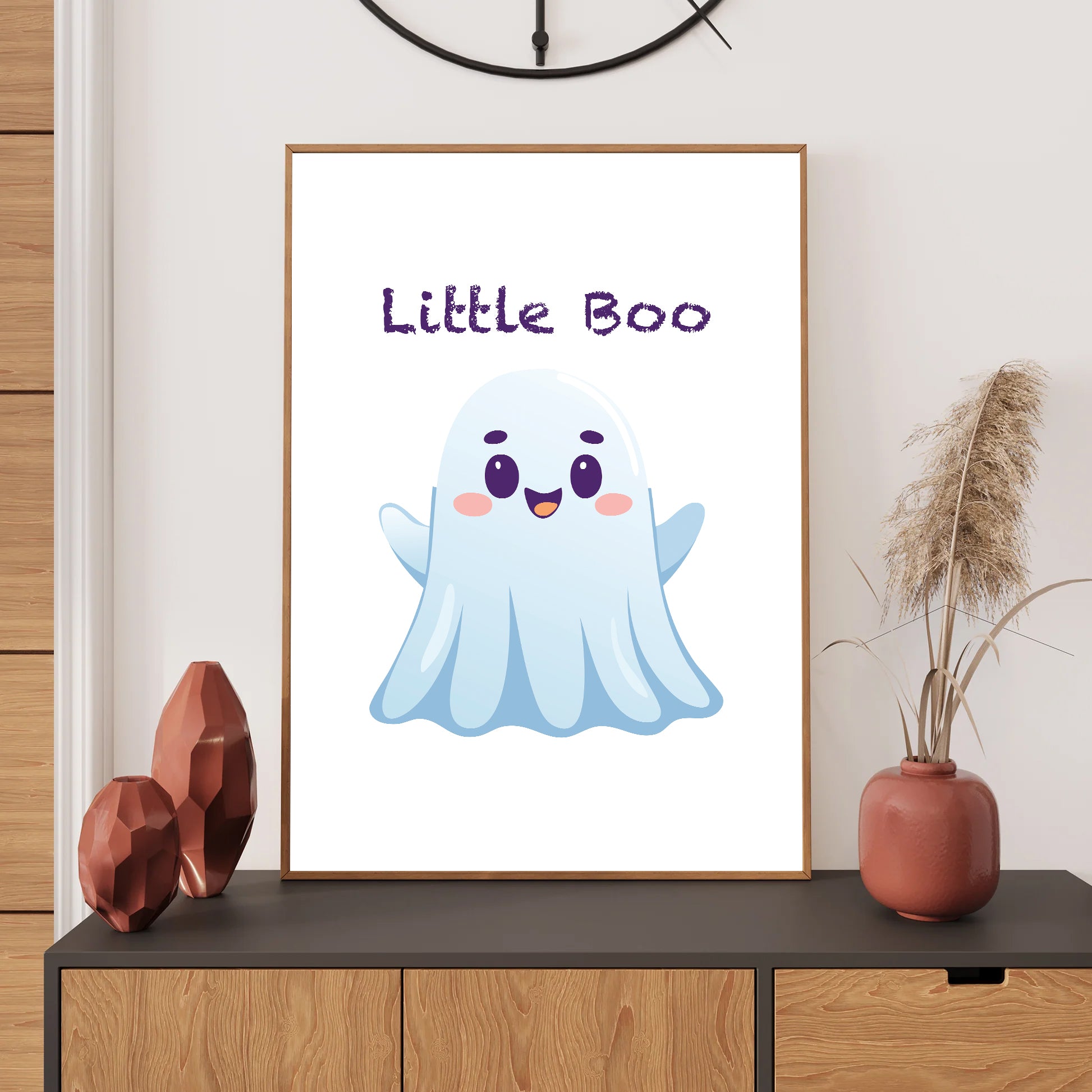 Framed artwork with a cartoon ghost and 'Little Boo' text on a wall above a wooden cabinet.
