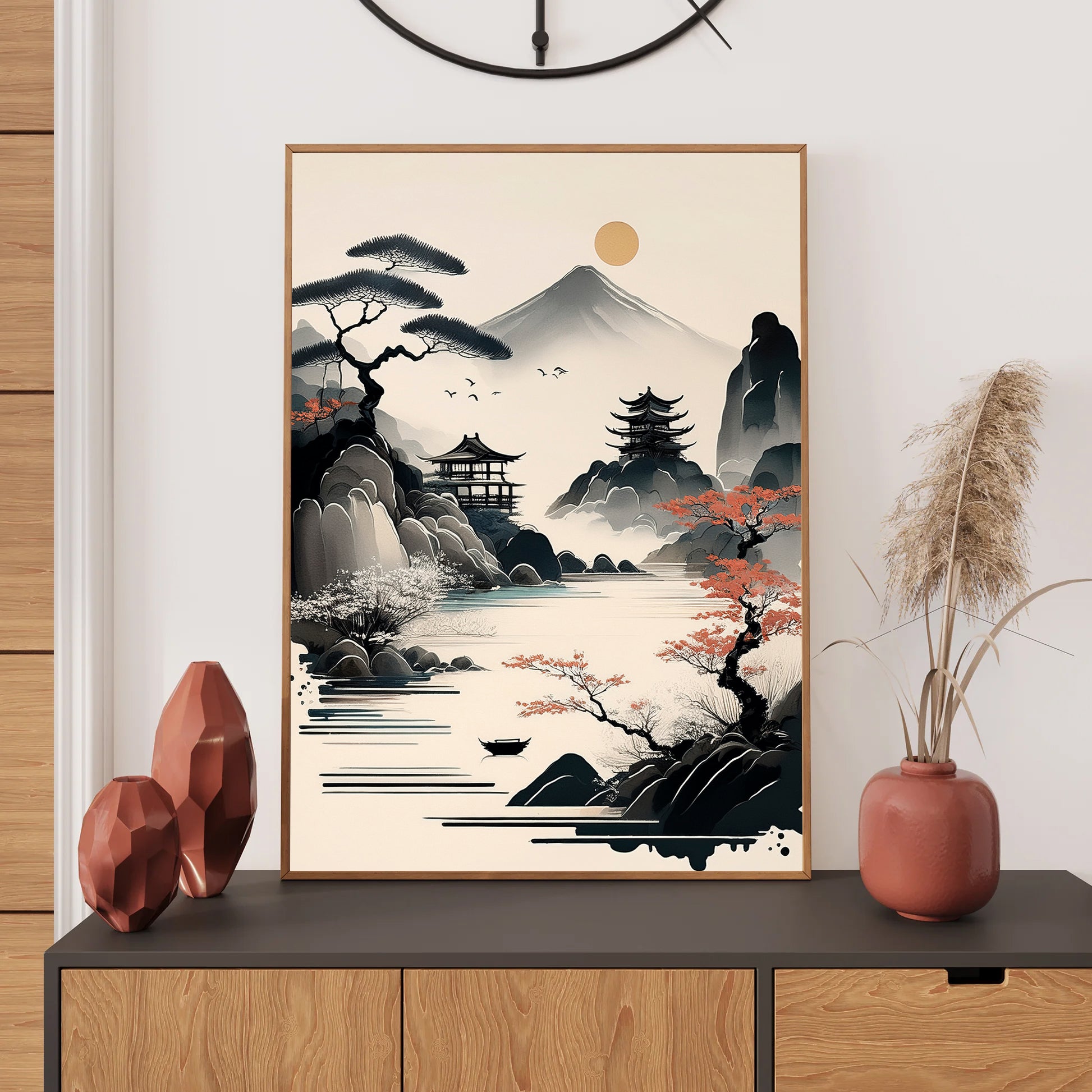 Framed artwork of a Japanese landscape with mountains and a temple on a wall above a wooden cabinet.
