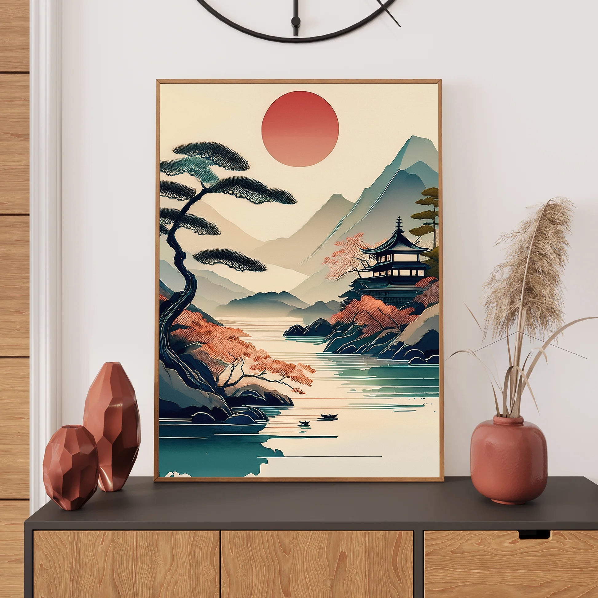 Framed artwork of a Japanese landscape with a red sun, mountains, and a temple on a wall above a console table.