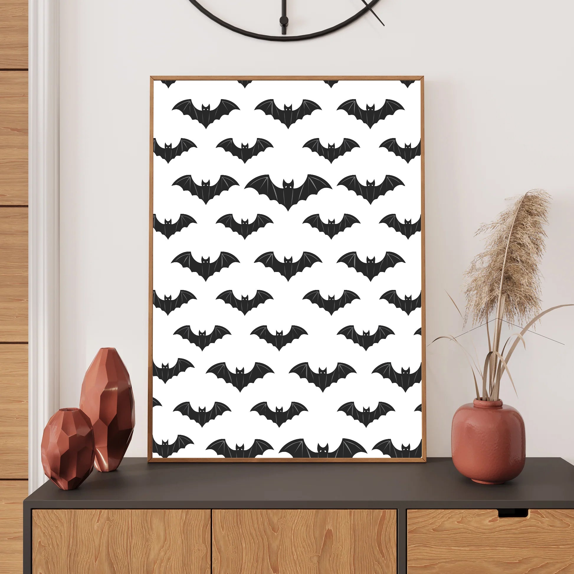 Framed poster with black bat pattern on a white background, displayed on a wooden shelf.